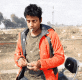 a man smoking a cigarette while wearing an orange jacket