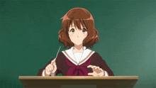 a girl in a school uniform is sitting at a desk holding a stick