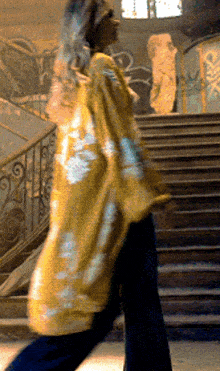 a woman in a yellow tie dye shirt is walking down a set of stairs