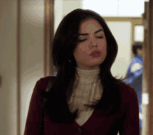 a woman with her eyes closed is wearing a maroon cardigan and a white blouse