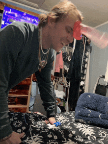 a man wearing a green shirt with a gold chain around his neck is playing a game with a red cup on his head