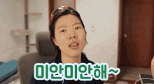 a woman is sitting in a chair with a green sign that says " 미안 미안해 "