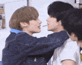 two boys are kissing each other with a stick in their mouths