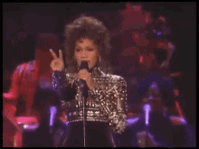a woman singing into a microphone in front of a band