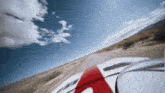 a car is driving down a desert road with a blue sky in the background
