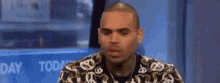 a man in a louis vuitton shirt is sitting in front of a television .