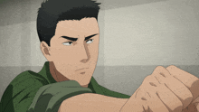 a man in a green shirt holds his fist up in the air