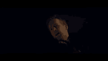 a man with a beard is looking down in the dark .