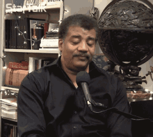 a man sitting in front of a microphone with a book called dictionary in the background