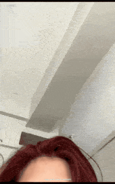 a woman with red hair is standing in front of a white wall