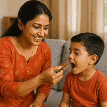 a woman is feeding a child a small piece of chocolate