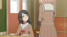 a girl in a school uniform sits at a desk in a classroom