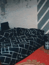 a bed with a black and white checkered blanket and a laptop on the nightstand