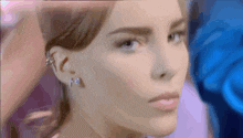 a close up of a woman 's face with a blue shirt in the background