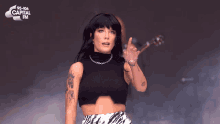 a woman in a black crop top and zebra print skirt performs on stage at capital fm