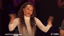 a woman stands in front of a microphone with her hands in the air and the words agt fantasy league on the bottom