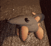 a stuffed animal that looks like an armadillo is sitting on a concrete surface .