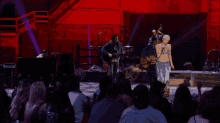 a man playing a guitar on a stage with a crowd watching