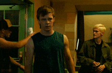 a man in a green tank top stands in front of a green door