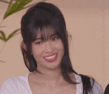 a close up of a woman 's face with a plant in the background .