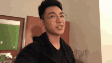 a young man wearing glasses and a black shirt looks at the camera