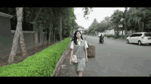 a girl in a school uniform is walking down a sidewalk .