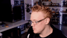 a man with red hair wearing glasses looks to the side