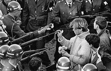 a man is holding a flower in front of a group of police officers .