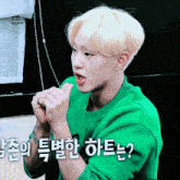 a young man wearing a green sweater with foreign writing on his arm