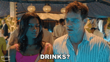 a man and a woman are standing next to each other and the man asks the woman " drinks "