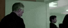 a man in a suit is standing in front of a white board in a room .