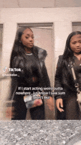 two women are standing next to each other in a bathroom and one of them is wearing a black vest .