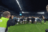 a man taking a picture of a group of soccer players on a field that says fly emirates
