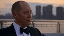 a man in a tuxedo with a bow tie looks at the camera