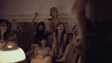 a group of women are sitting on a couch and one is holding a glass of wine