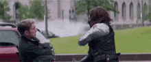 a man and a woman are standing next to each other on a sidewalk and fighting .