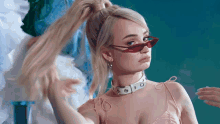 a blonde woman wearing red sunglasses and a choker