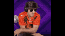 a man wearing a red shirt with palm trees on it is dancing in front of a microphone .