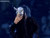 a woman wearing a mask with horns and the name thekamdreesen on the bottom right