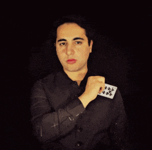 a man in a black shirt is holding a playing card with the number 25 on it
