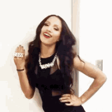 a woman wearing a black dress and a necklace has the word boss on her ring