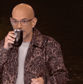 a man in a leopard print jacket is drinking from a cup with a skull on it .