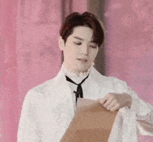 a young man in a white shirt and tie is holding a piece of paper in his hand .
