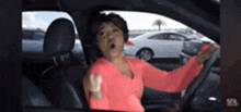 a woman in a pink sweater is sitting in a car