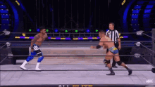 two men are wrestling in a wrestling ring while a referee looks on .