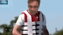 a man wearing a life vest is standing in the water .