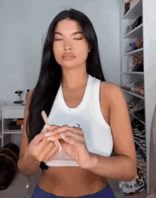 a woman wearing a white tank top and blue shorts is holding a pink object .