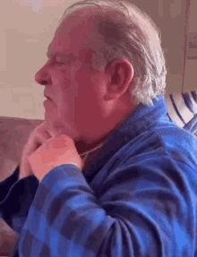 a man in a blue robe is sitting on a couch with his hands on his face