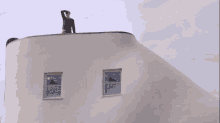 a man stands on top of a white building with two windows