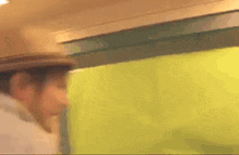a man wearing a hat and a white shirt is standing in a room .